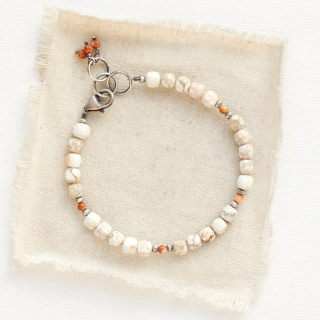 The white magnesite and red malachite gemstone bracelet styled on tan linen