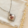 The mexican fire opal heart and garnet necklace styled on a tan plate with linen and dried grass