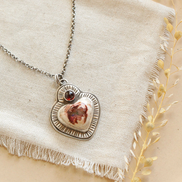The mexican fire opal heart and garnet necklace styled on a tan plate with linen and dried grass