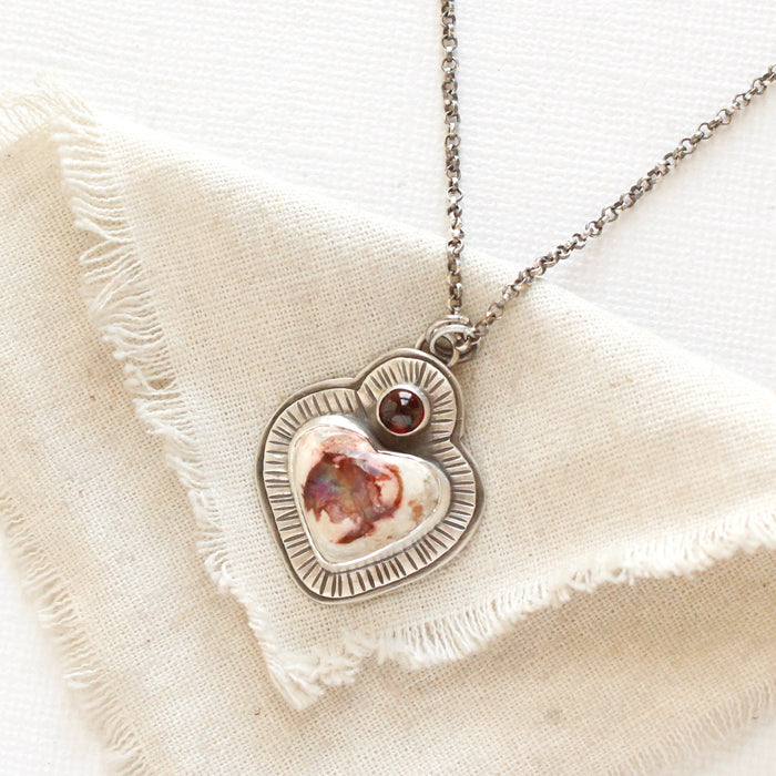 The sacred heart necklace styled on tan linen