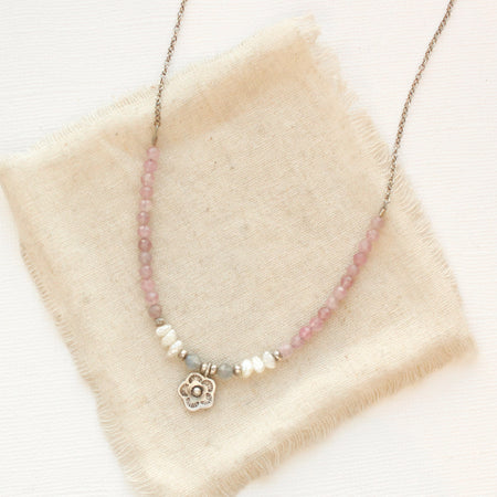 The blush mini cactus flower necklace styled on tan linen