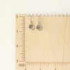 The mini cactus flower charm earrings on a wooden ruler for size reference