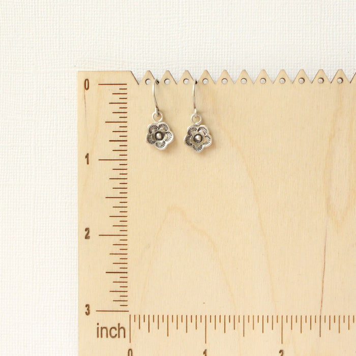 The mini cactus flower charm earrings on a wooden ruler for size reference