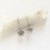 The mini cactus flower lobe hugger earrings styled on rolled linen