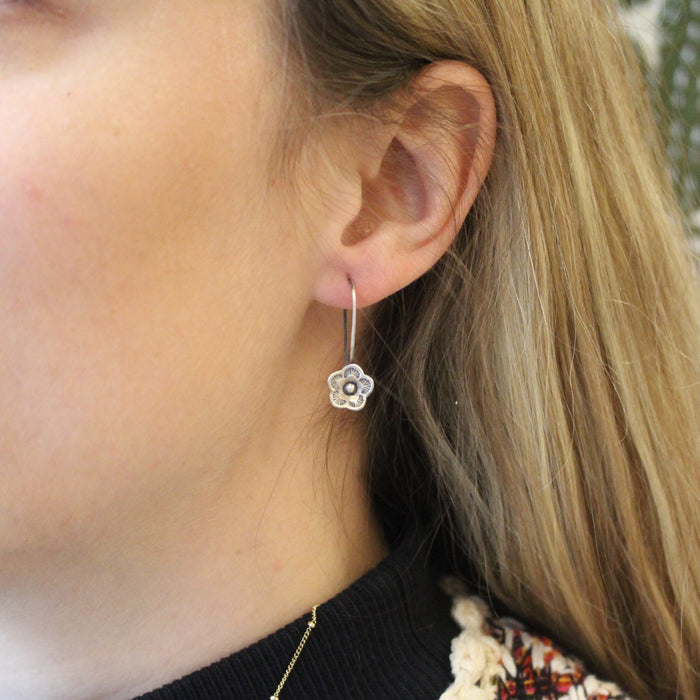 The mini cactus flower lobe hugger being worn in an ear