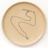The mini cactus flower necklace styled on a tan plate to show the adjustable lobster clasp closure