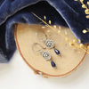 The mini cactus flower sodalite lantern earrings styled on wood with blue velvet and dried grass
