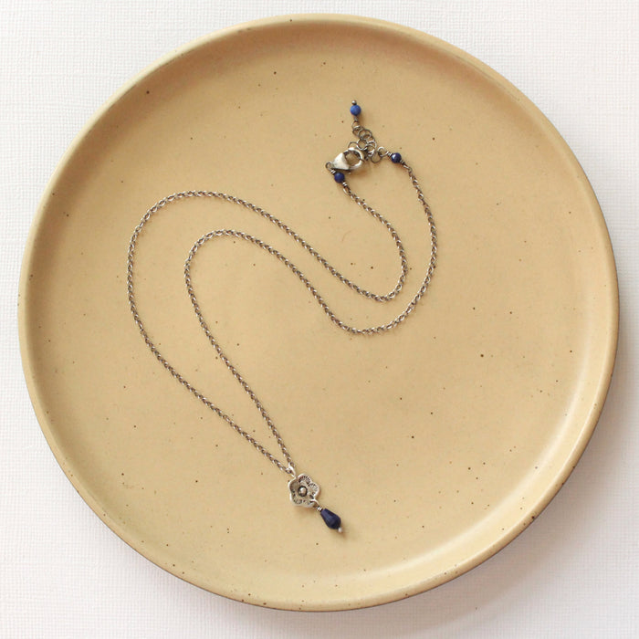 The mini cactus flower sodalite lantern necklace styled on a tan plate to show the adjustable lobster clasp closure