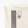 A mini soar earring next to a ruler for size reference