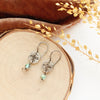 The mini soar turquoise dangle earrings styled on wood with orange velvet and dried grass