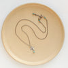 The mini soar and turquoise necklace styled on a tan plate to show the adjustable lobster clasp closure