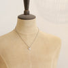 A mannequin wearing the mini sprout and pearl charm necklace