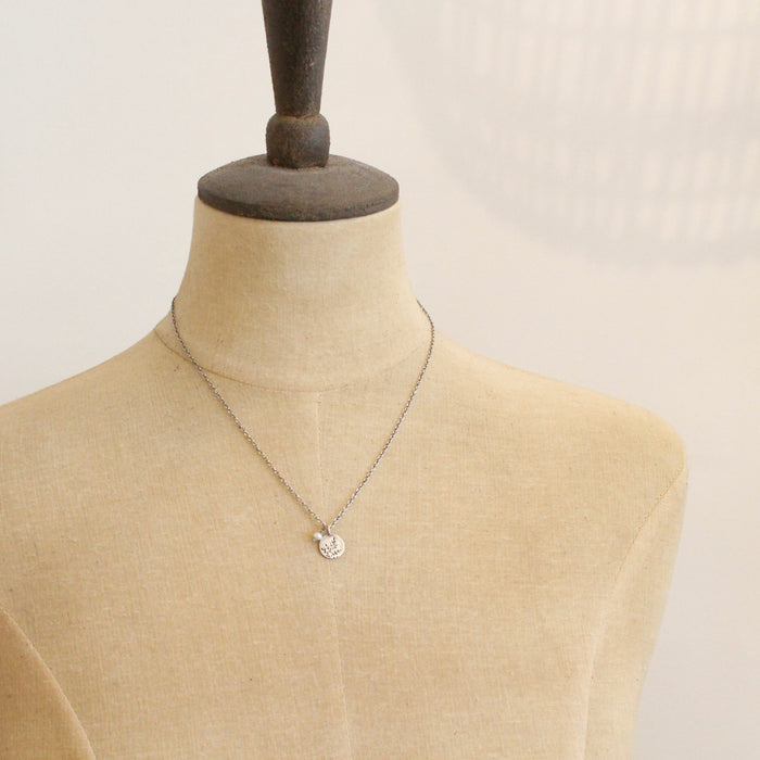 A mannequin wearing the mini sprout and pearl charm necklace