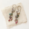 The mini sprout rainbow tourmaline earrings styled on tan linen