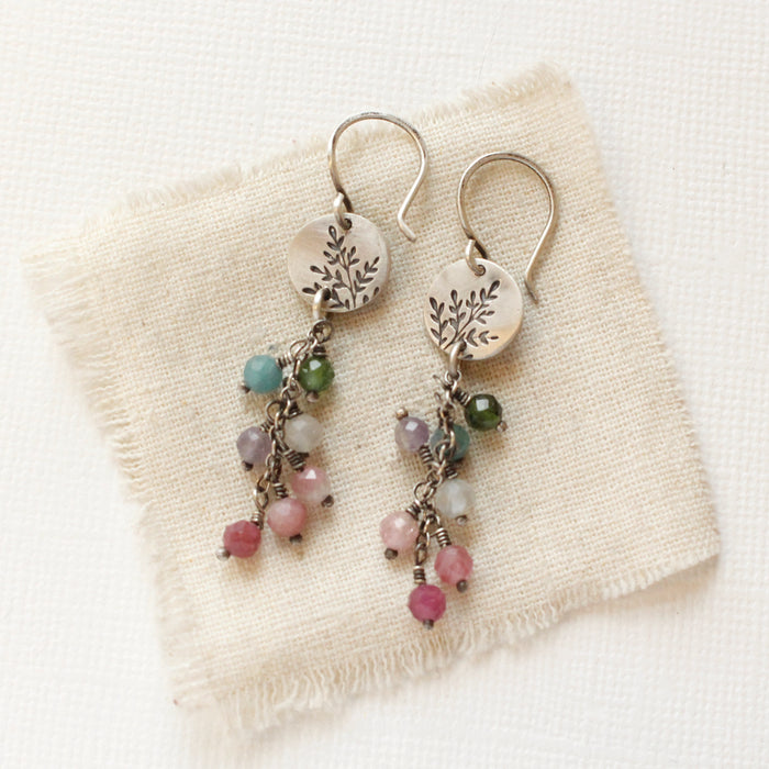 The mini sprout rainbow tourmaline earrings styled on tan linen