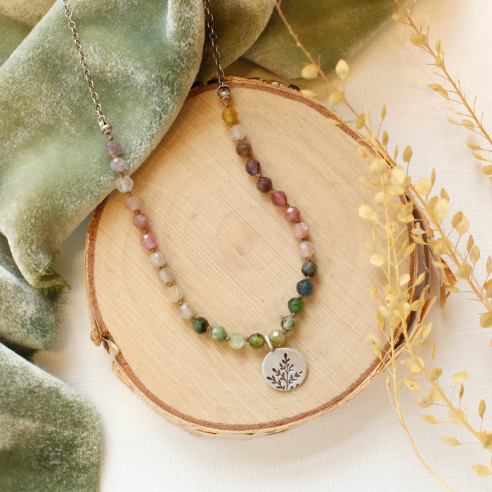 The mini sprout rainbow tourmaline necklace styled on wood with green velvet and dried grass