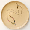 The mini sprout rainbow tourmaline necklace styled on a plate to show the adjustable lobster clasp closure