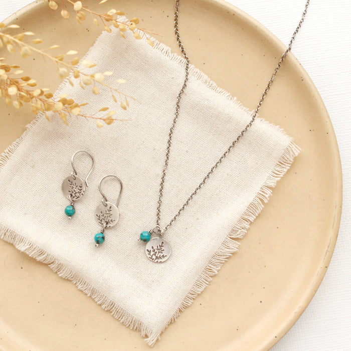 The mini sprout turquoise necklace styled on a tan plate with the matching earrings