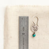A mini sprout turquoise dangle earring next to a ruler for size reference