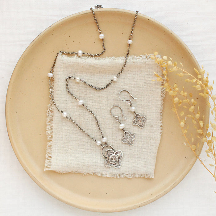 The mini talara pearl earrings styled with the matching necklace on a tan plate with linen and dried grass