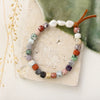 The mixed gem, pearl, and leather stretch bracelet styled on a tan rock with green velvet and dried grass