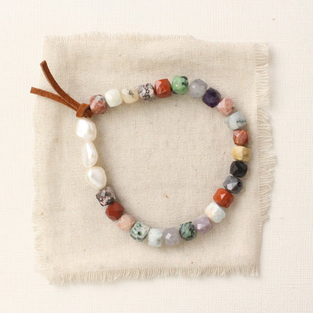 The mixed gem, pearl, and leather stretch bracelet styled on tan linen