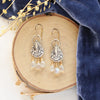 The vienna earrings styled on wood with blue velvet and dried grass