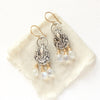 The mixed metal teardrop and moonstone earrings styled on tan linen