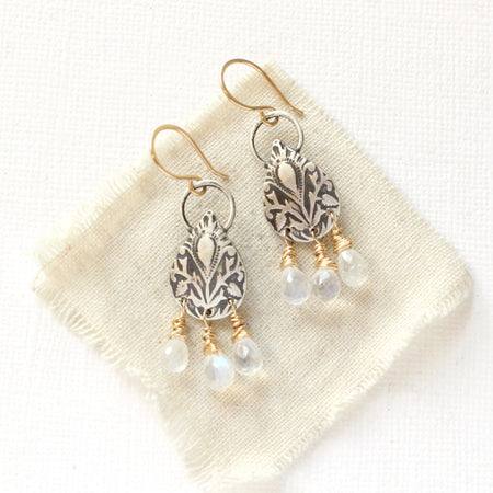 The mixed metal teardrop and moonstone earrings styled on tan linen