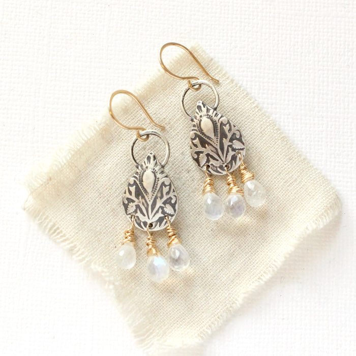 The mixed metal teardrop and moonstone earrings styled on tan linen