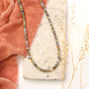 The mixed opal necklace styled on a tan rock with orange velvet and dried grass