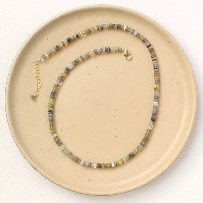 The mixed opal necklace styled on a tan plate to show the adjustable lobster clasp closure