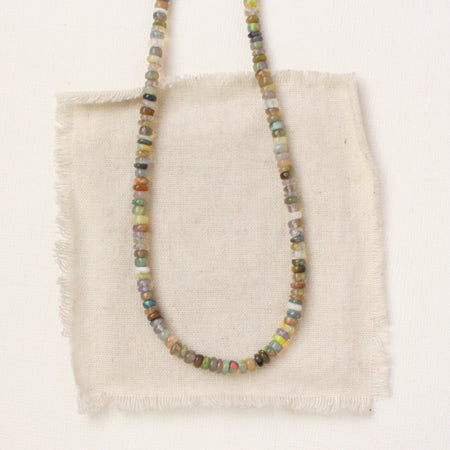 The mixed opal necklace styled on tan linen