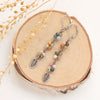 The long kaleidoscope leaf earrings styled on wood with dried grass
