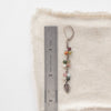 A kaleidoscope leaf earring next to a ruler for size reference