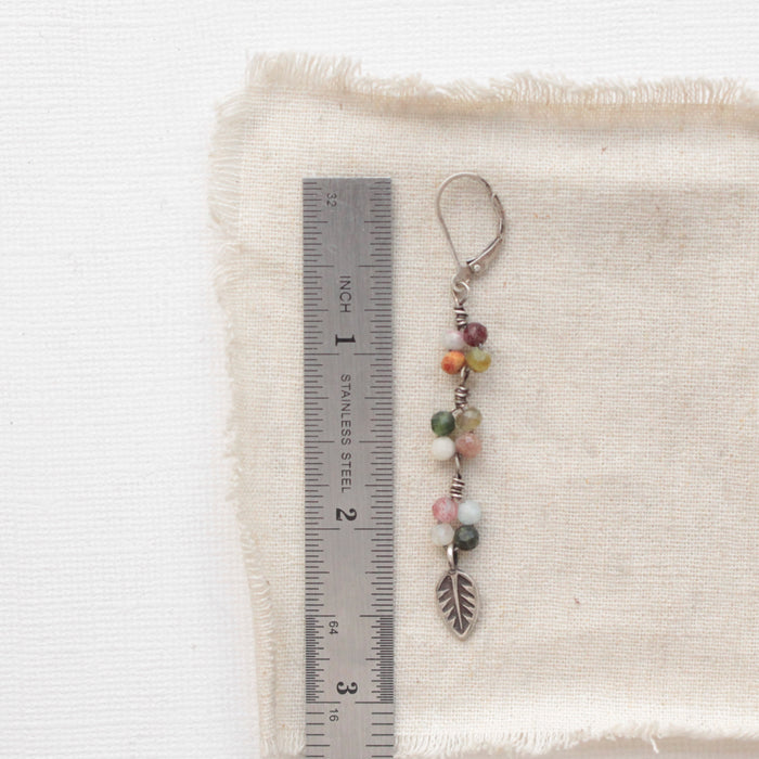 A kaleidoscope leaf earring next to a ruler for size reference