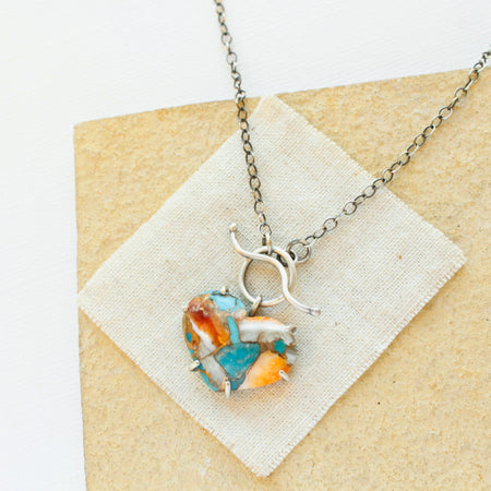 The mohave turquoise heart necklace styled on a tan rock with linen