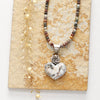 The mohave white buffalo turquoise heart and succulent necklace with the mixed gemstone chain option styled on a tan rock with dried grass