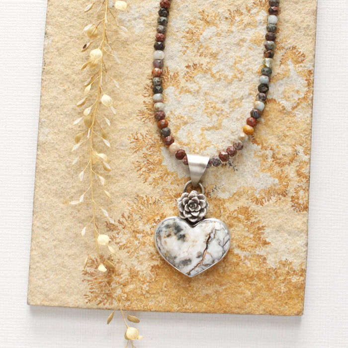 The mohave white buffalo turquoise heart and succulent necklace with the mixed gemstone chain option styled on a tan rock with dried grass