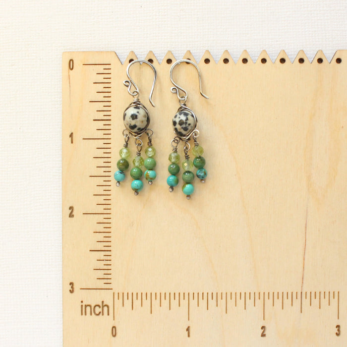 The monica chandelier earrings on a wooden ruler for size reference