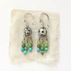 The monica chandelier earrings styled on tan linen