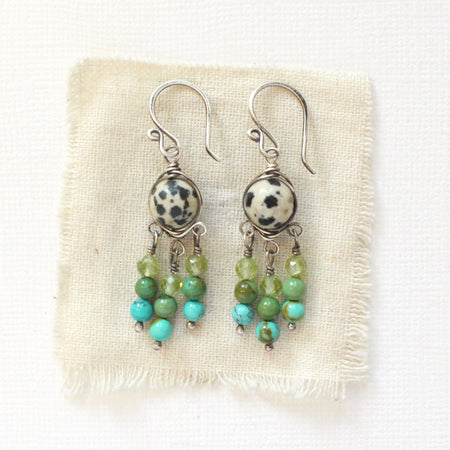 The monica chandelier earrings styled on tan linen