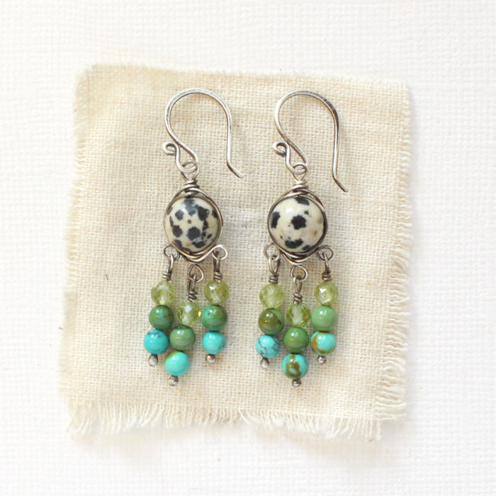 The monica chandelier earrings styled on tan linen