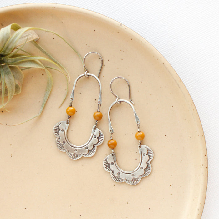 The mookaite columbine hoop earrings styled on a tan plate with an air plant