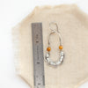 A mookaite columbine hoop earring next to a ruler for size reference