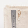A moonstone drop earring next to a ruler for size reference