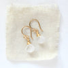 The moonstone drop earrings with shepherd hooks styled on tan linen