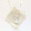 The silver moonstone drop necklace styled on tan linen