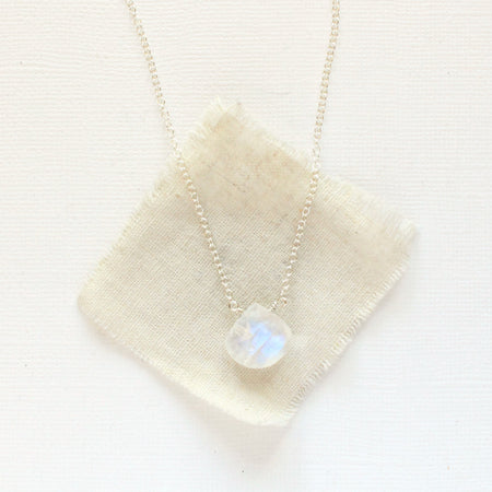 The silver moonstone drop necklace styled on tan linen