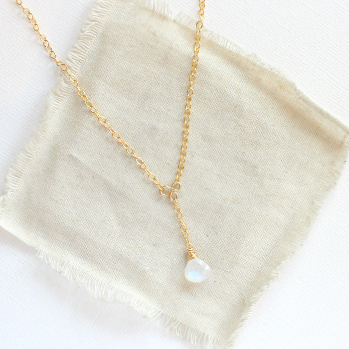 The moonstone gold lariat necklace styled on tan linen